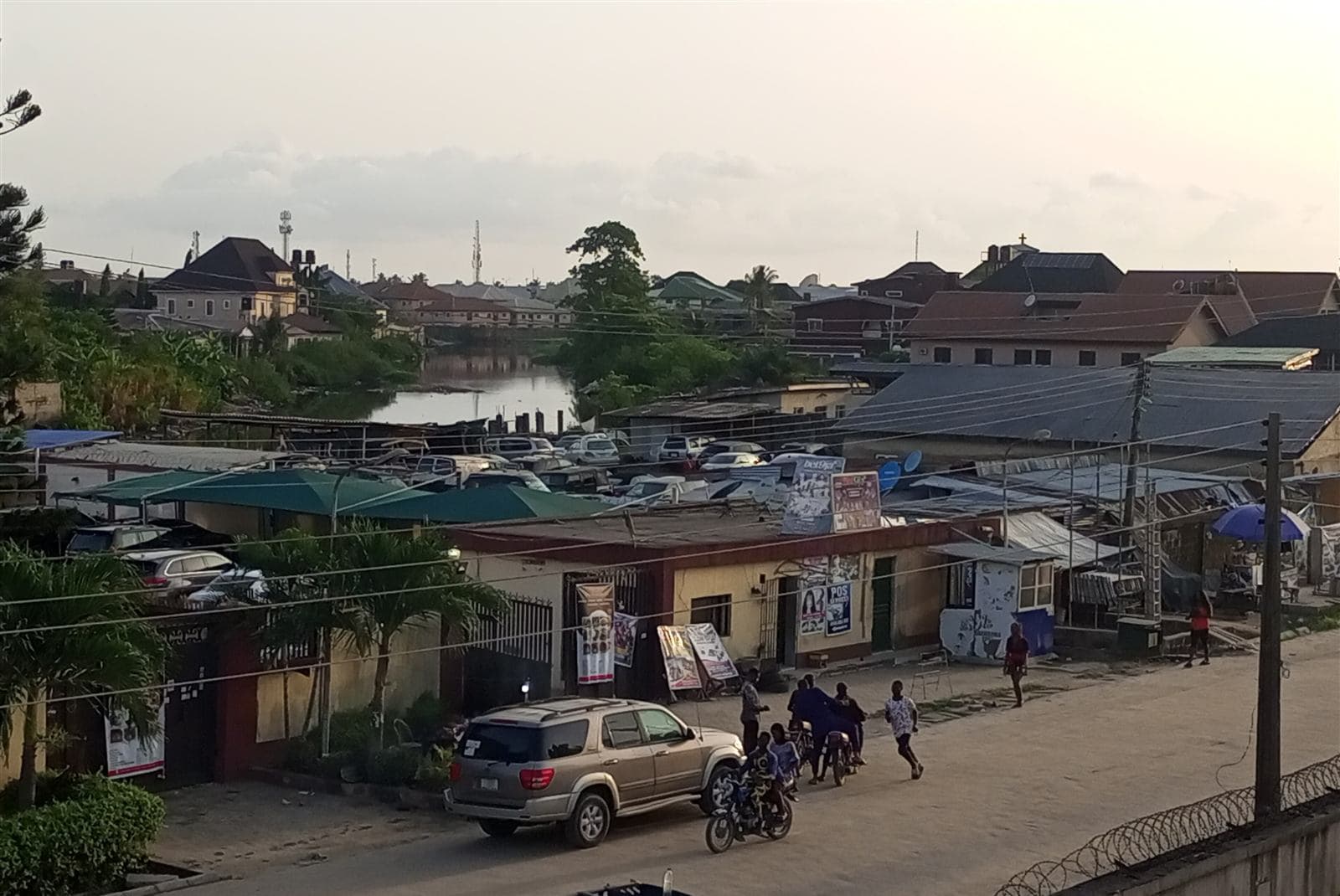 A Festac street at dusk, with a canal and houses behind